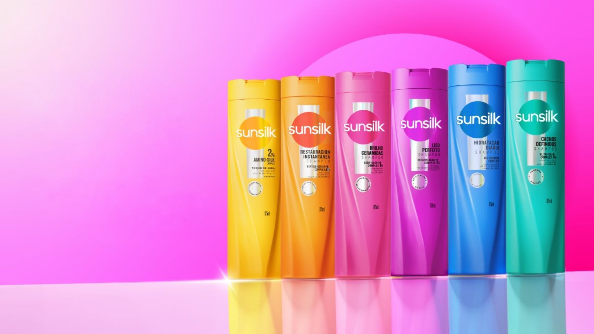 Cinque flaconi di shampoo Sunsilk in colori vivaci (arancione, rosa, fucsia, verde e turchese) allineati su sfondo rosa sfumato, con logo Sunsilk in alto a destra.