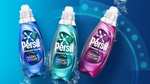 Un flacone blu, turchese e rosa di Persil Wonder Wash su uno sfondo verde acqua.
