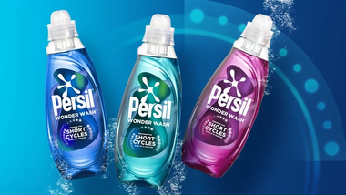 Un flacone blu, turchese e rosa di Persil Wonder Wash su uno sfondo verde acqua.