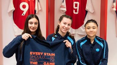 Ragazze nello spogliatoio dell’Arsenal con una maglietta con la scritta “Every stain should be part of the game”, campagna sulla normalizzazione delle macchie nel gioco.